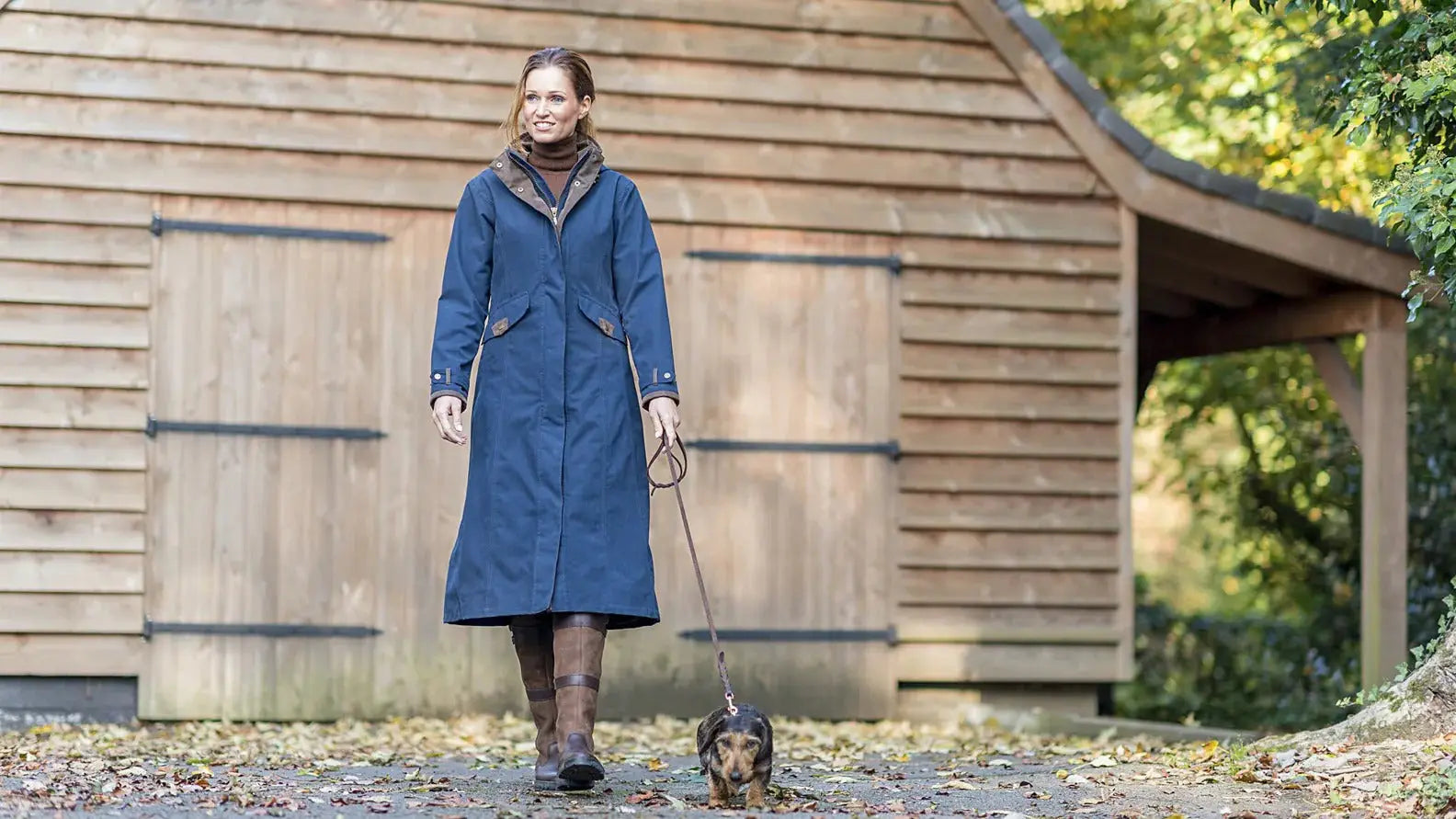 Woman in a blue coat walking a small dog, showcasing Baleno Kensington ladies longer length.