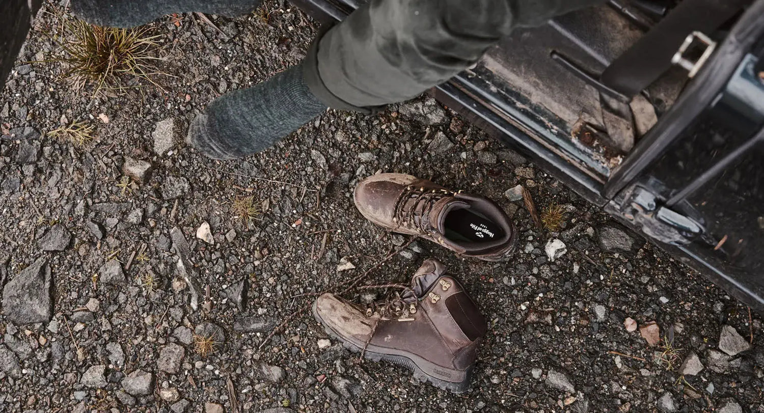 Worn-out, dusty walking boots on rocky ground showing the need for care and support.