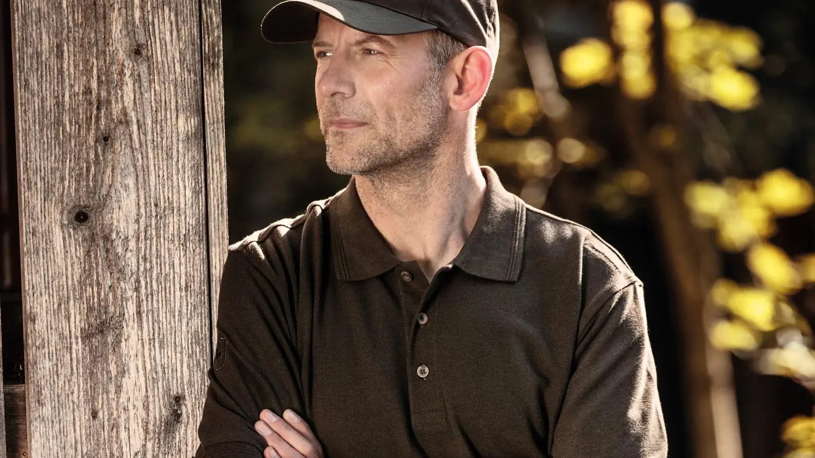 Man in a dark polo shirt and baseball cap, showcasing classic fashion basics.