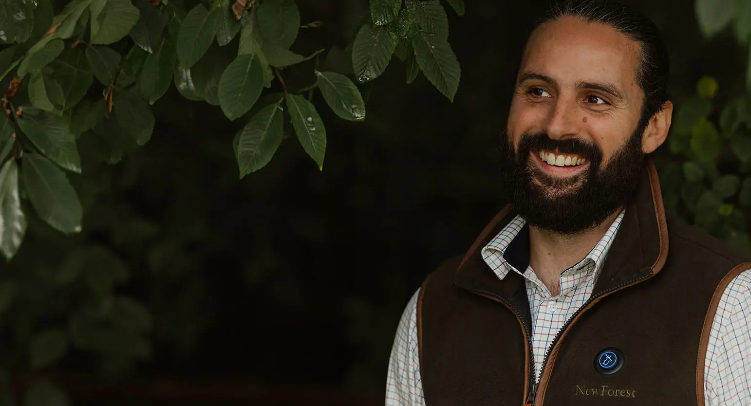 Smiling bearded man in a brown vest over a shirt, showcasing Forest Heat heated gilets.