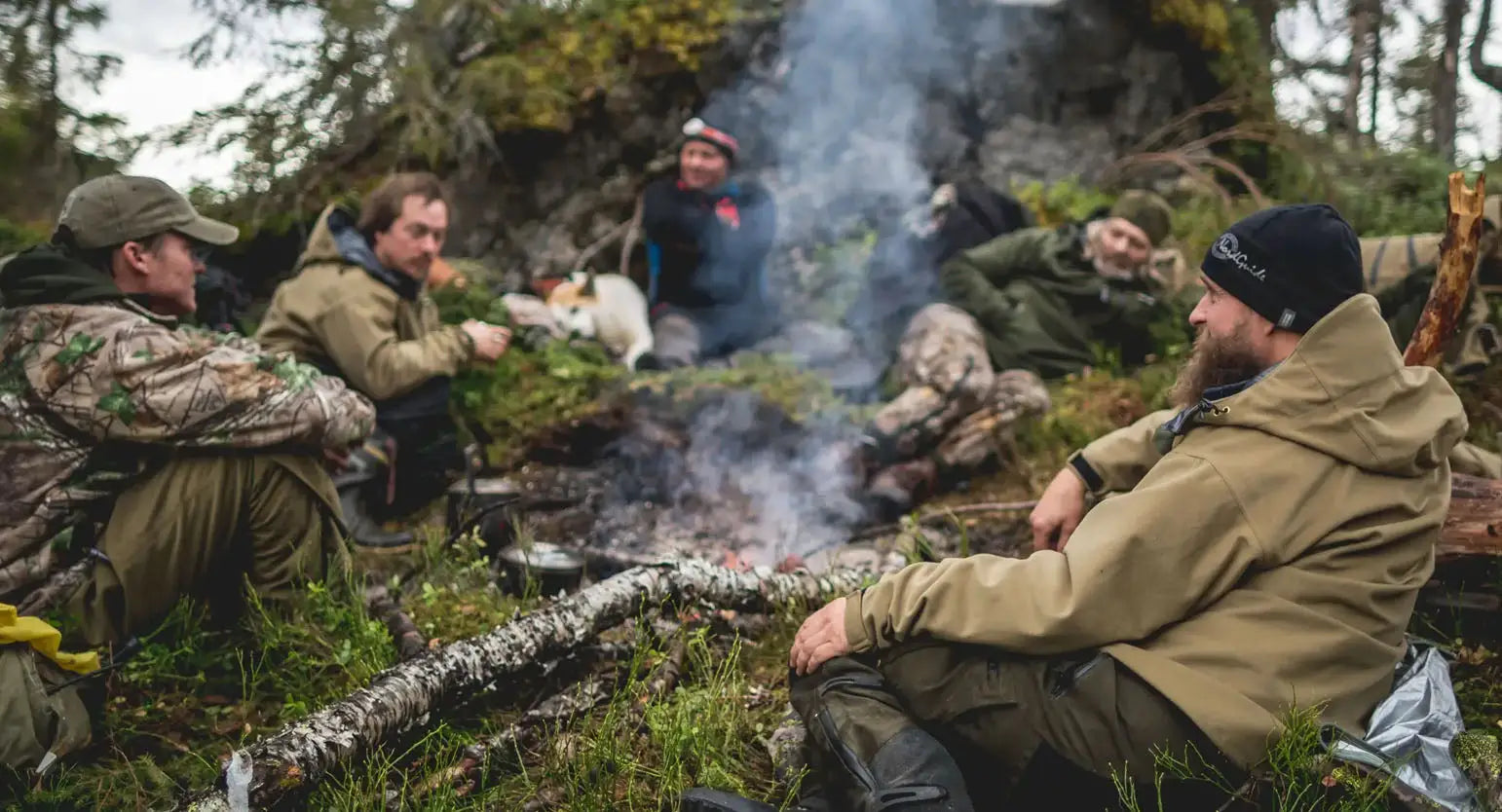 Group of people enjoying a campfire in a forest, showcasing Swazi’s vibrant world of country clothing.