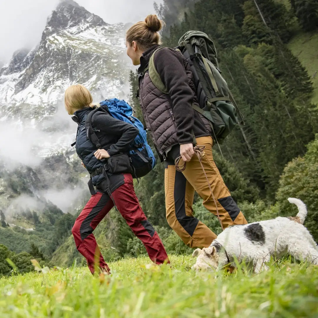 Two hikers in Lady Ann Trousers walking a dog in a stunning mountain landscape