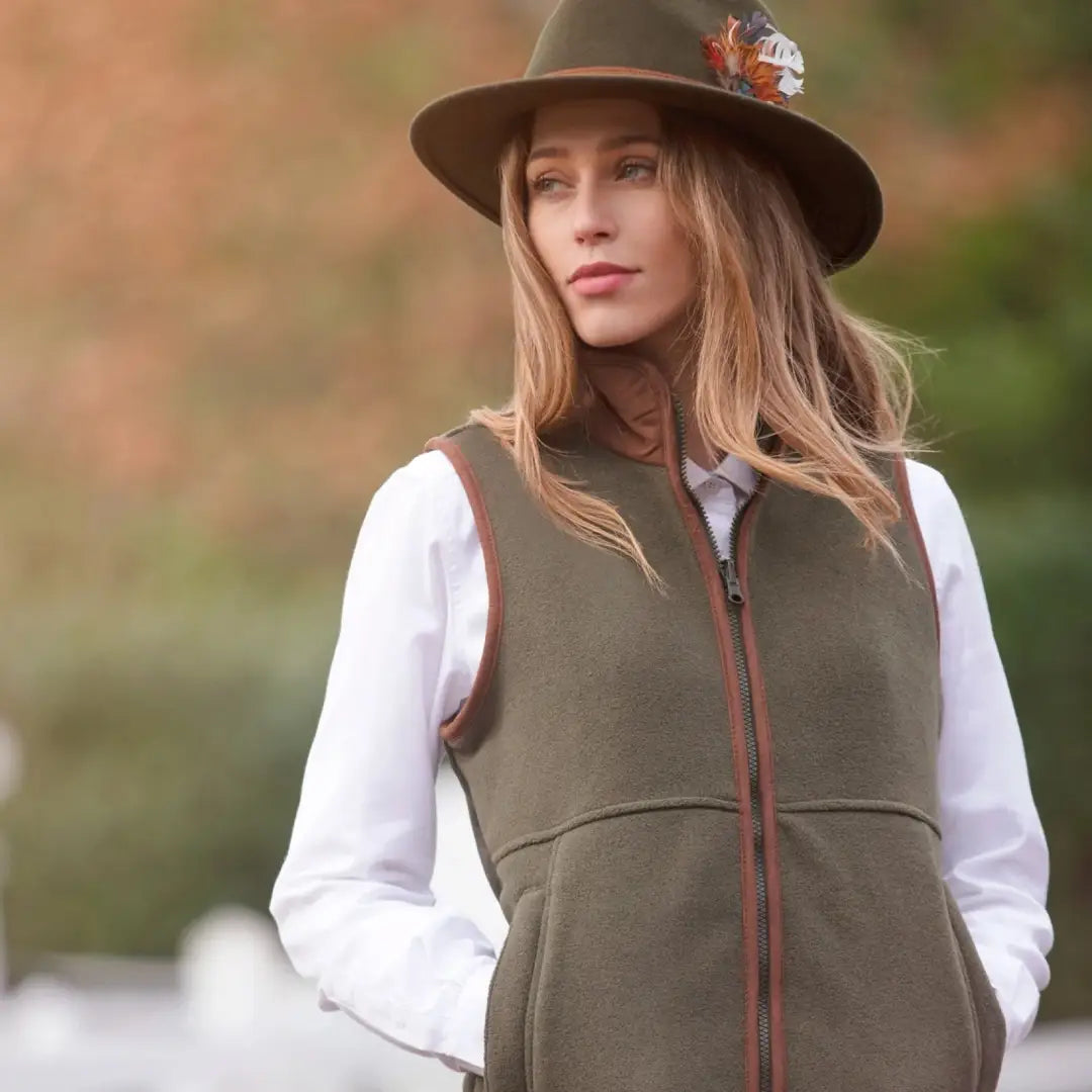 Woman in a brown hat and olive green vest showcasing Alan Paine Aylsham Ladies Fleece Gilet