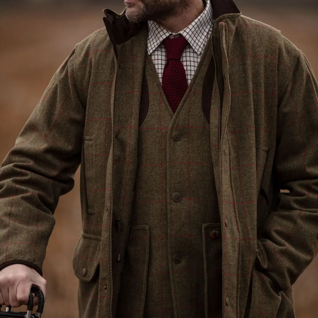 Man in a checkered shirt and Alan Paine Combrook vest with a stylish red tie