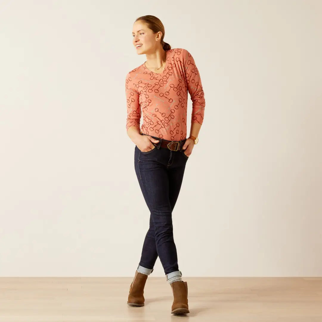 Woman in salmon lace top and jeans showcases Ariat Burnt Brick Bit T-Shirt for country clothing