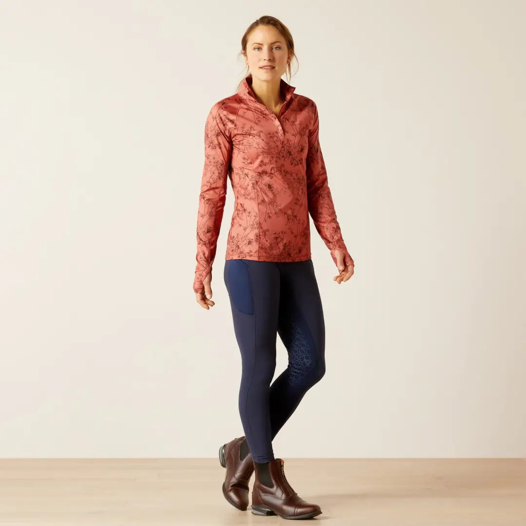 Woman in pink patterned top, navy leggings, and brown boots for stylish country clothing