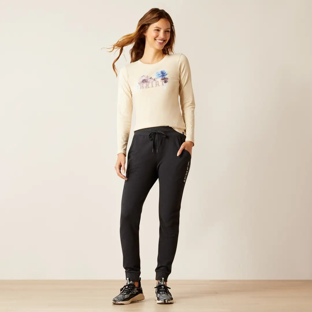 Woman in a cream floral sweater and dark jogger pants, rocking the Ariat Memento Jogger style