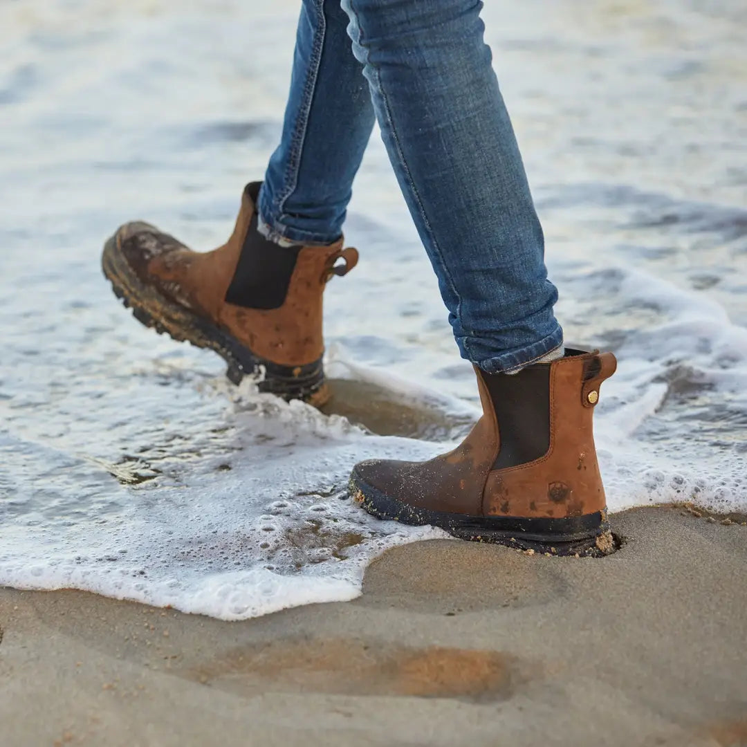 Brown leather Chelsea boots in ocean waves, perfect for country clothing adventures outdoors