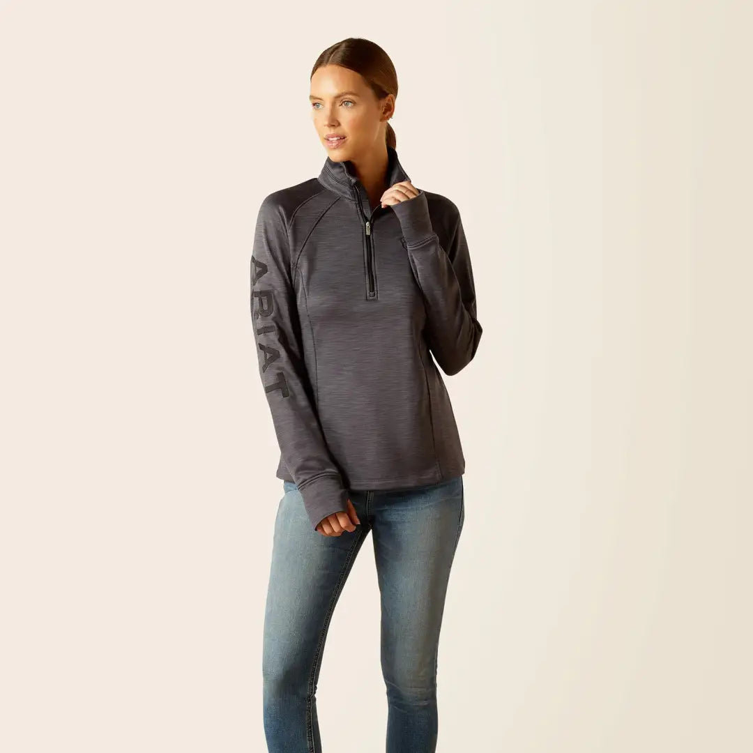 Woman in dark gray Ariat Womens Tek Team 1/2 Zip sweatshirt with blue jeans for outdoor adventures