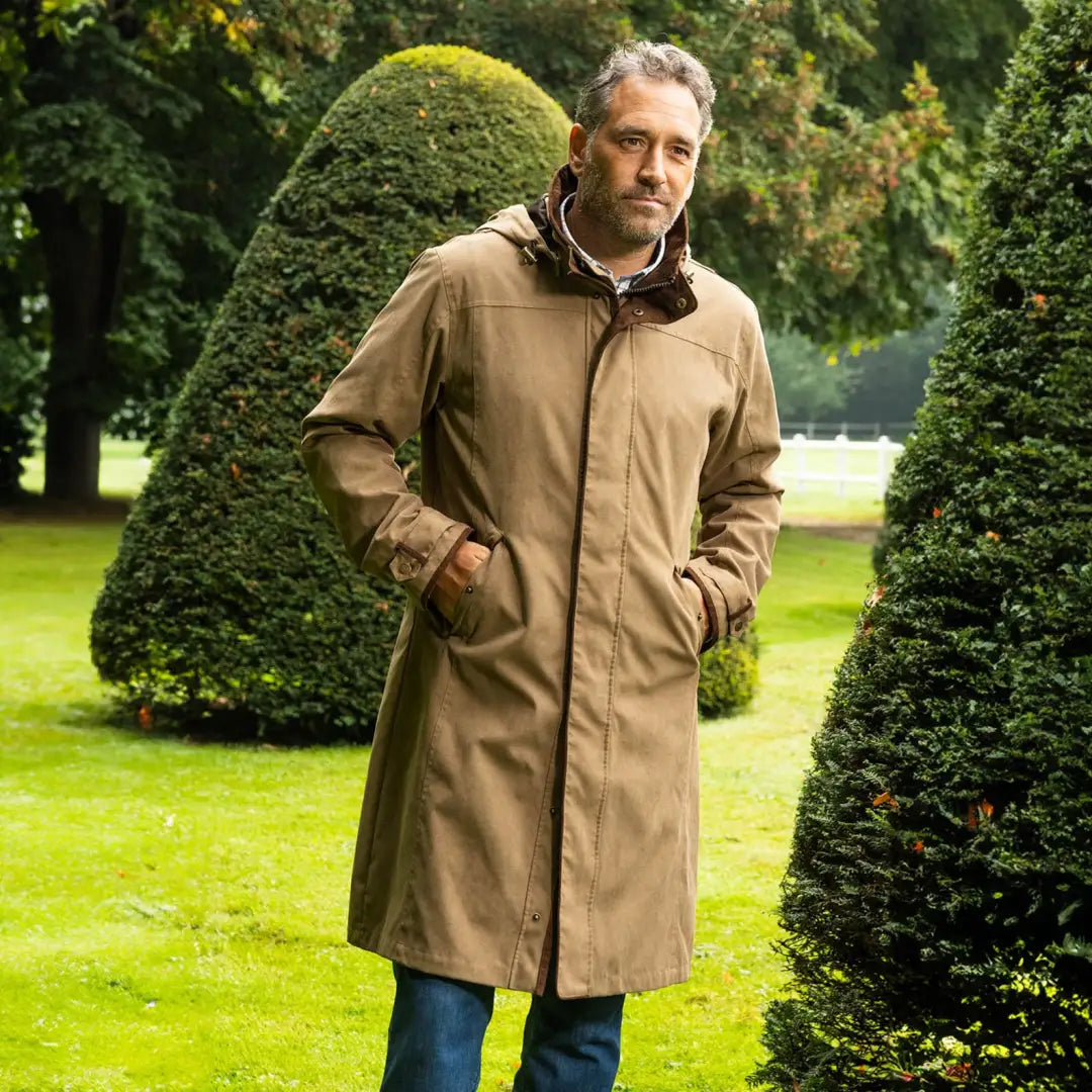 Man in a tan trench coat in a garden, perfect for successful Livingstone country clothing