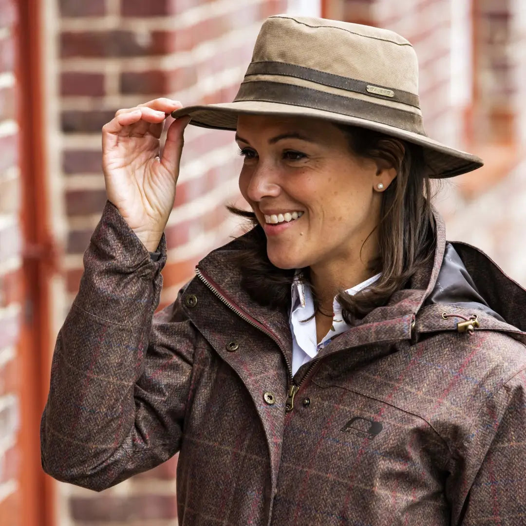 Smiling woman in beige fedora and plaid jacket wearing Baleno Edith Waterproof Hat