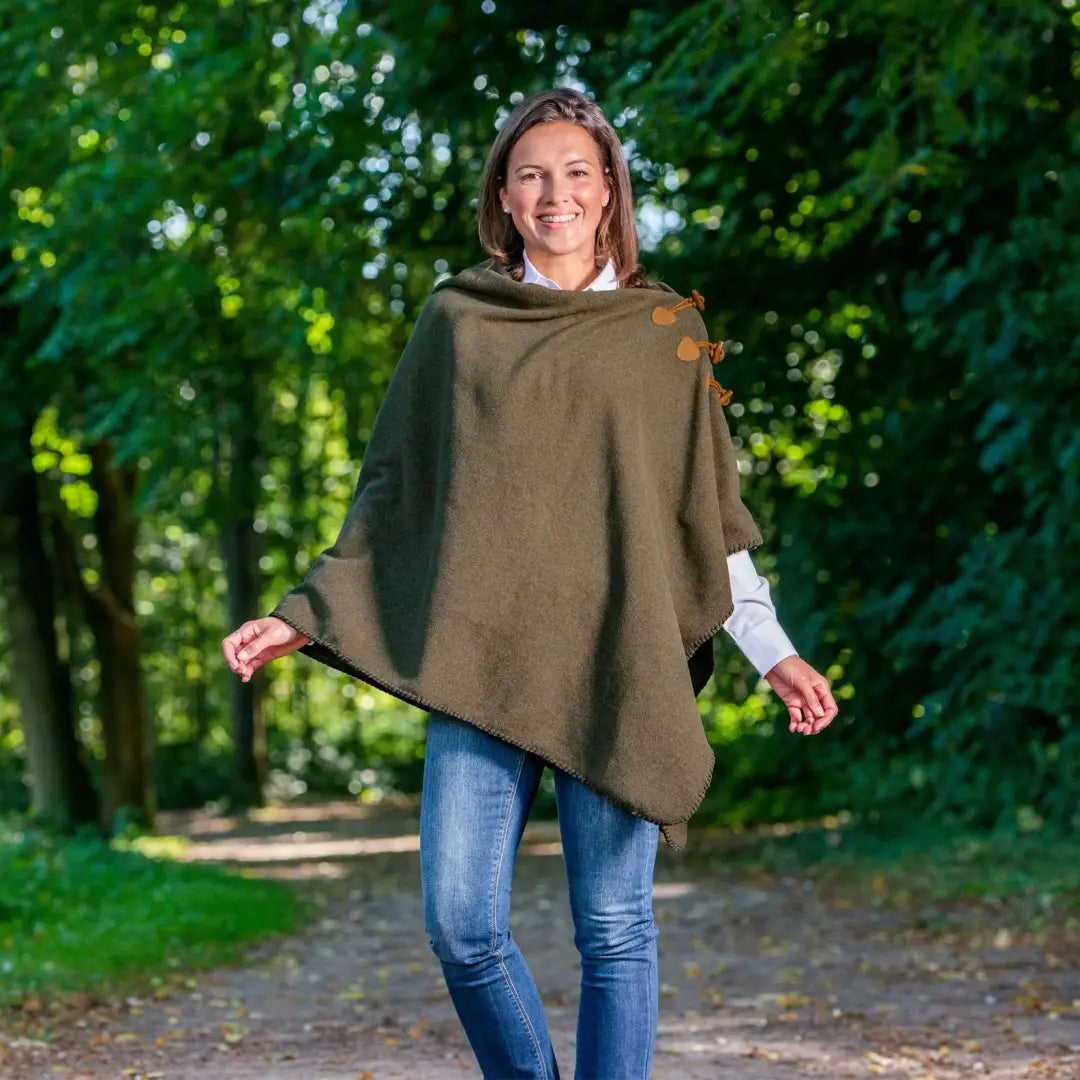 Smiling woman in an Olive Green Baleno Elite Fleece Poncho over jeans outdoors