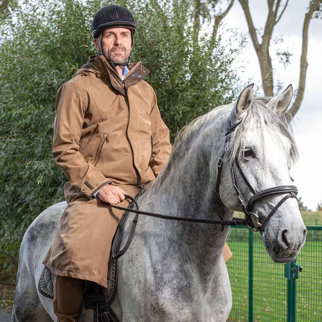 Rider in a helmet and coat on a gray horse sporting Baleno Livingstone Drovers Coat