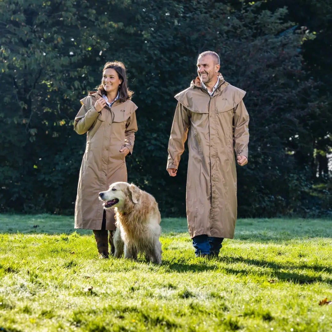 Couple in matching beige trench coats walking a Golden Retriever, showcasing Baleno Oxford Ladies