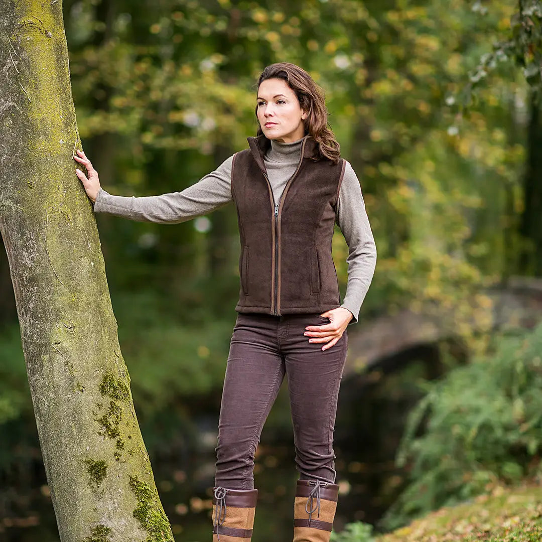 Woman in Baleno Sally Ladies Fleece Bodywarmer by a tree, showcasing cozy outdoor style