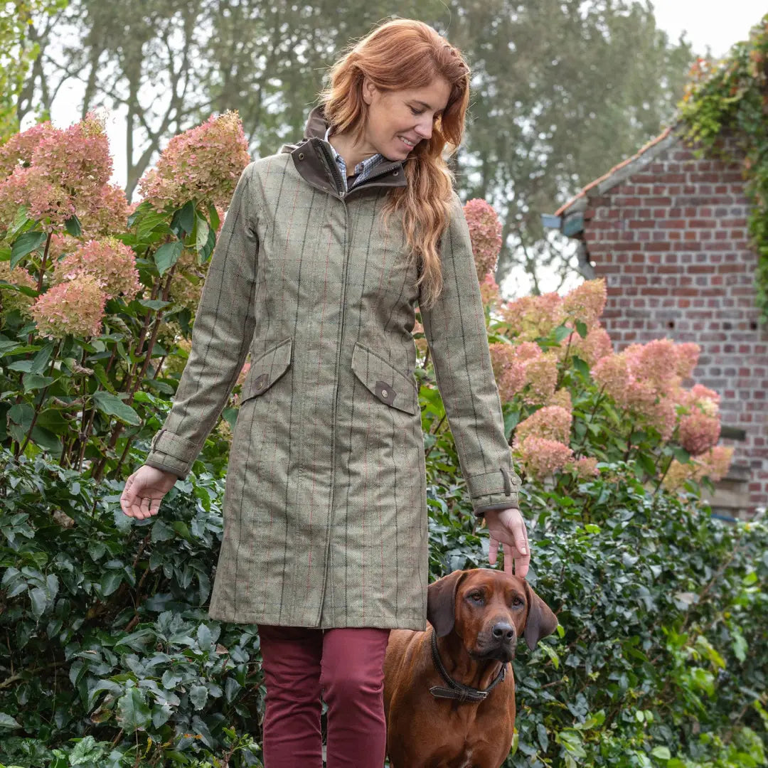 Woman in a green Baleno printed tweed coat walking her brown dog outdoors