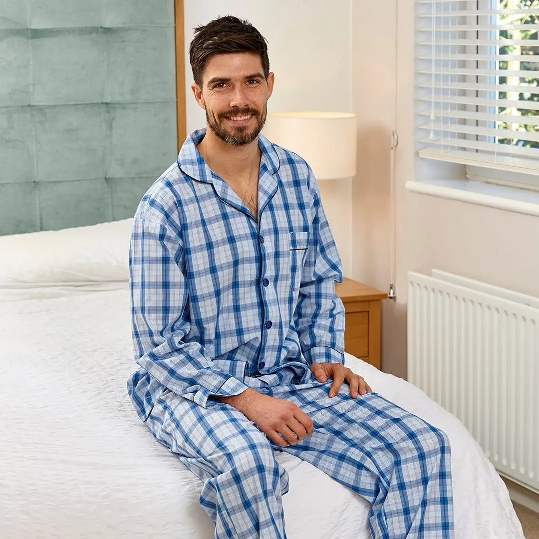 Man in blue and white plaid pajamas relaxing on bed in Champion Marlow Pyjamas