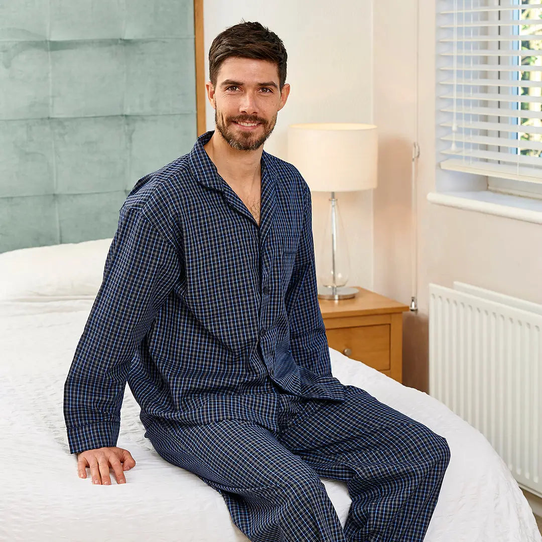 Man in blue checkered pajamas relaxing on a bed in Champion Marlow Pyjamas