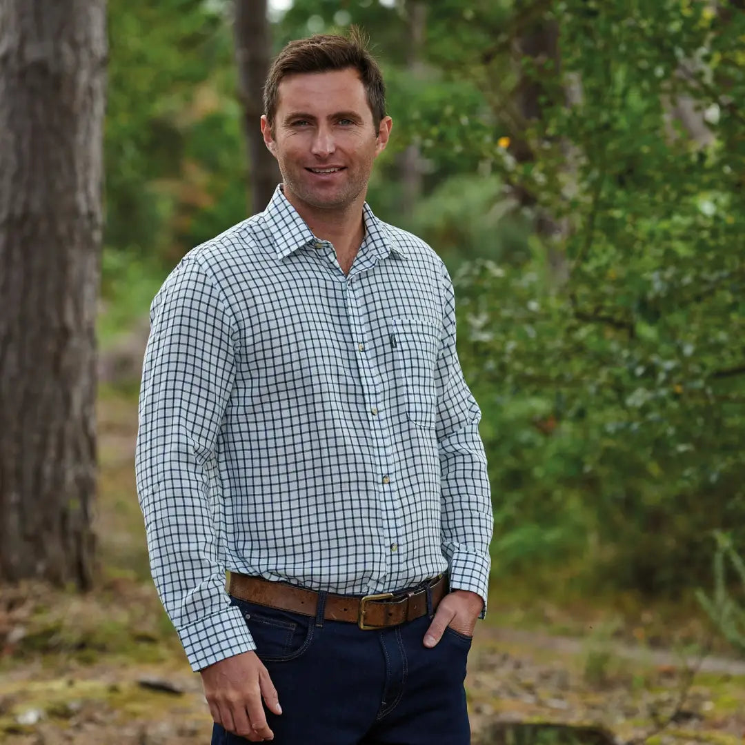 Man in a checkered Champion Salisbury Shirt and jeans standing outdoors