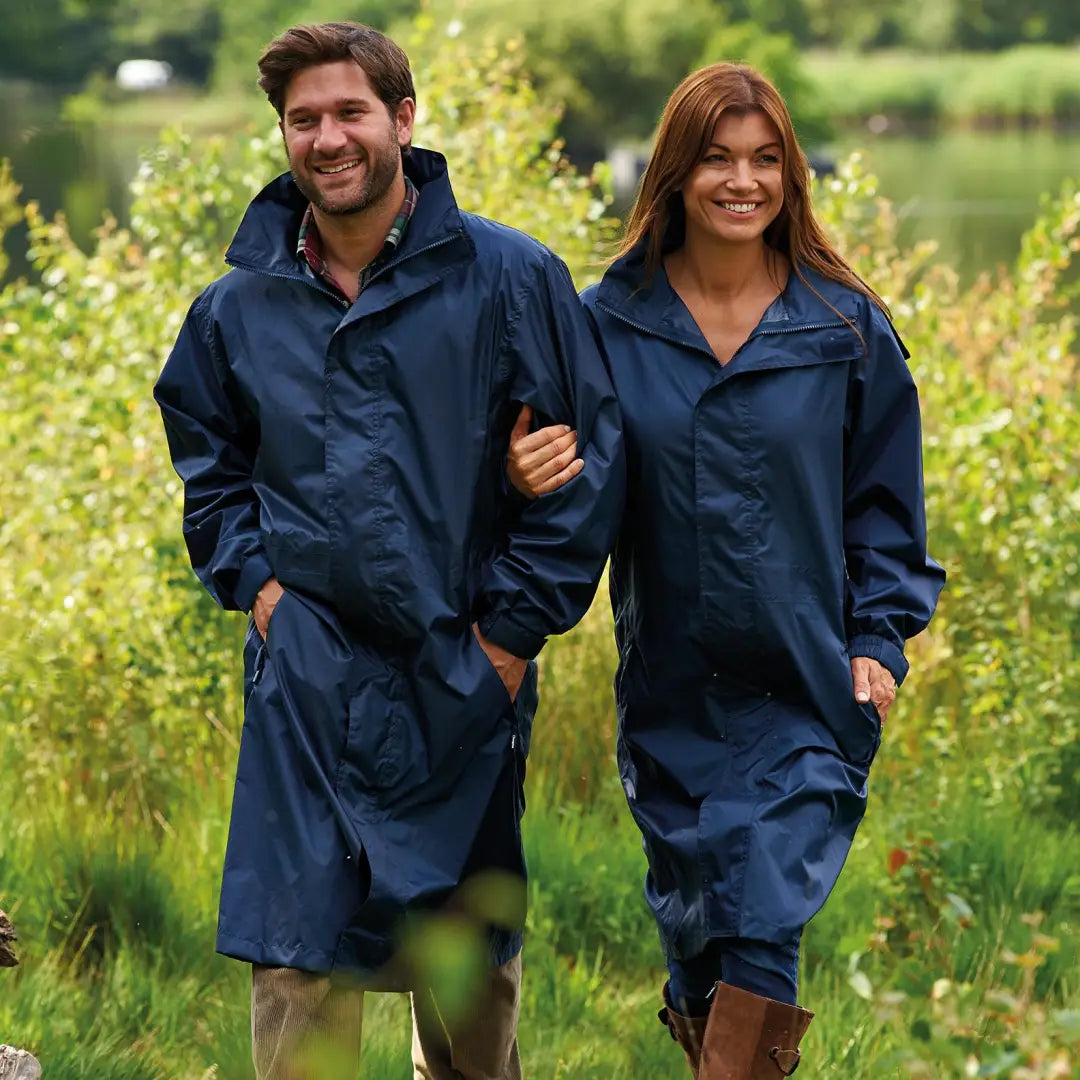 Two people in matching Champion Storm Long Coats stroll through tall grass