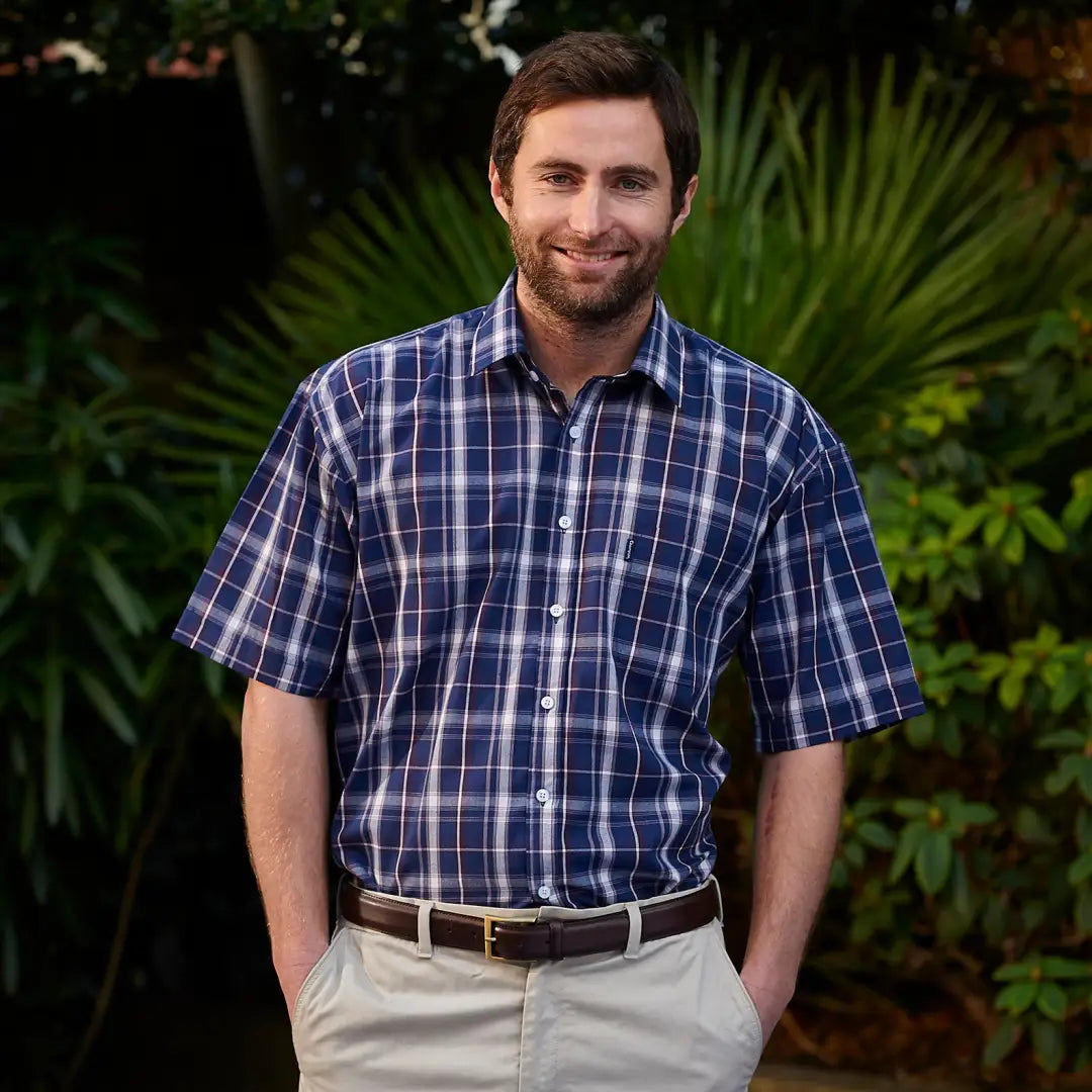 Smiling man in a blue plaid Champion Whitby short sleeved shirt and khaki pants