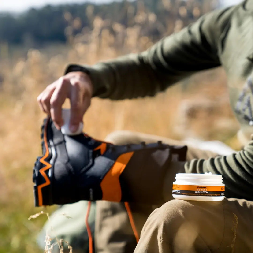 Person holding a stylish motorcycle helmet with orange accents for Crispi Conditioning Cream