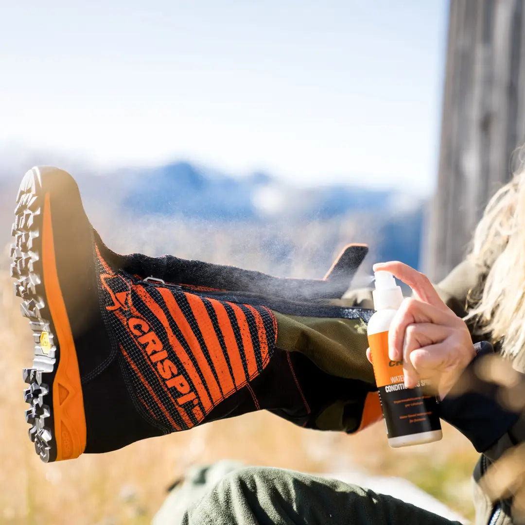 Colorful ski boot with orange and black stripes getting Crispi Waterproofing Spray