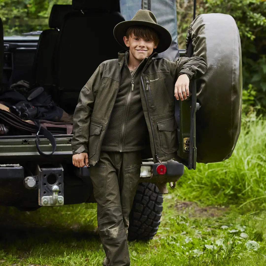 Person in olive green outdoor gear and hat next to a vehicle wearing a Chasse Fleece Jacket