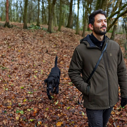 Man walking a black dog in the forest wearing a Deerhunter Denver Winter Jacket