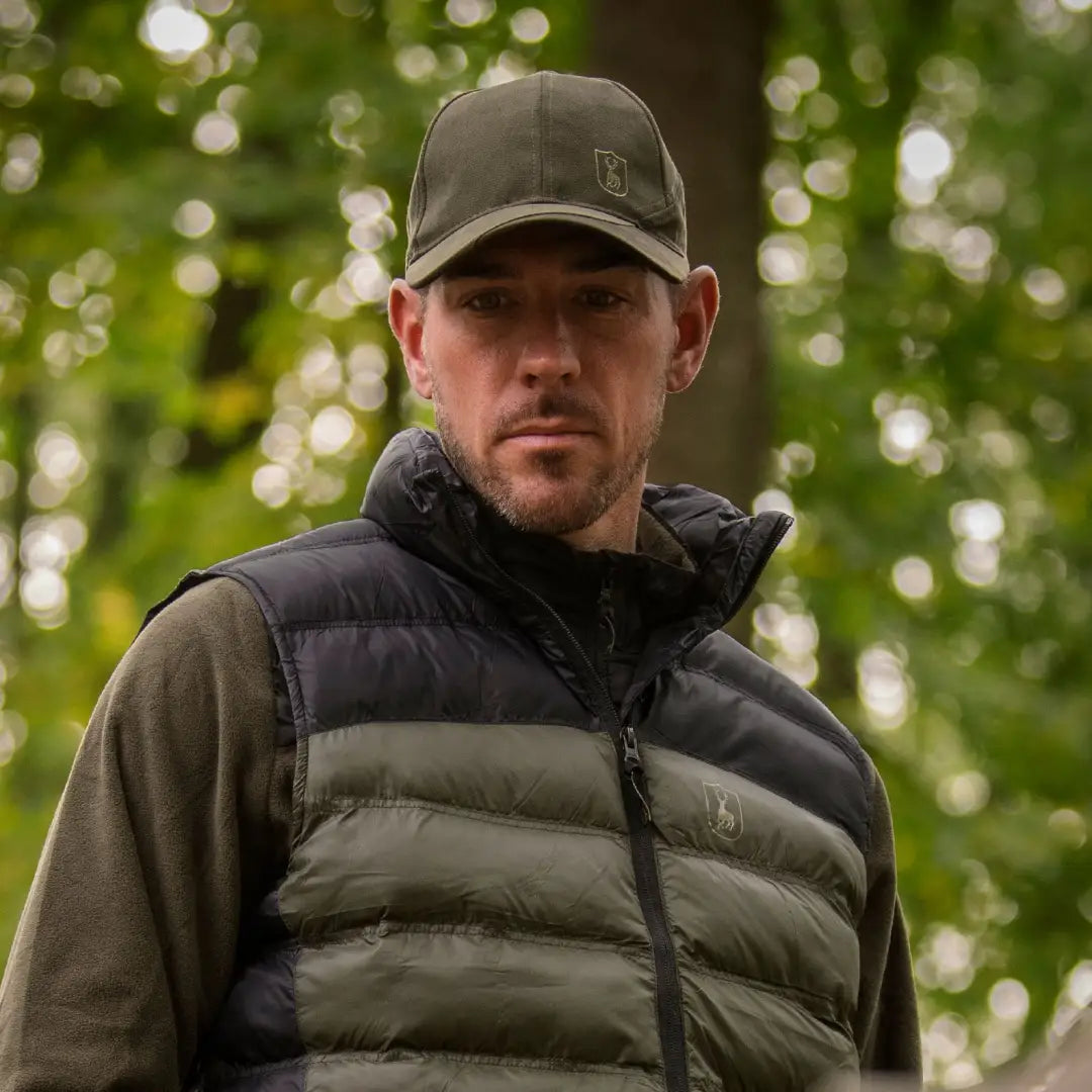 Man outdoors in a baseball cap and puffy vest sporting the Eagle Cap, hunting essentials