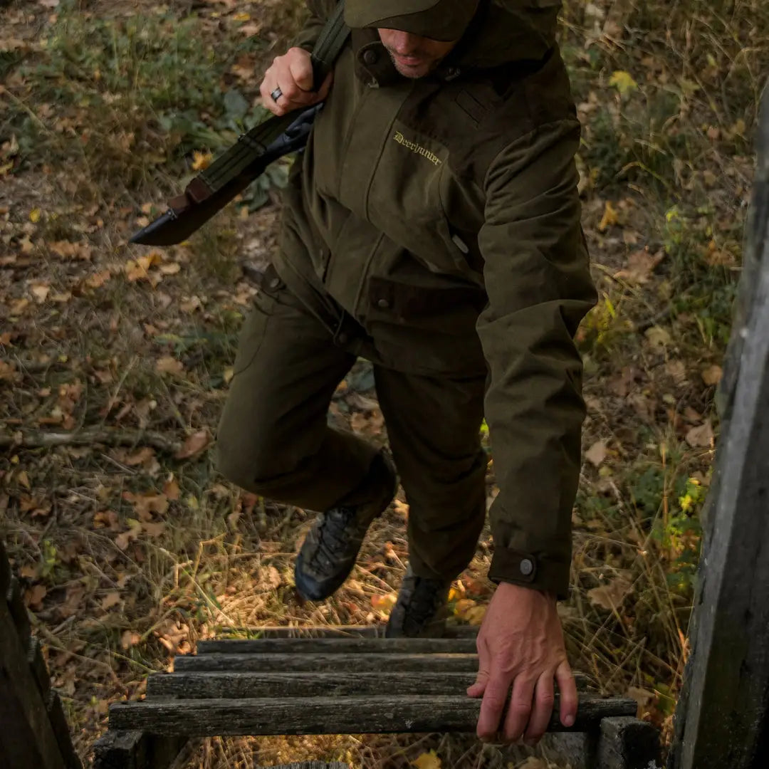 Person in military-style gear climbing wooden steps wearing Deerhunter Eagle Trousers