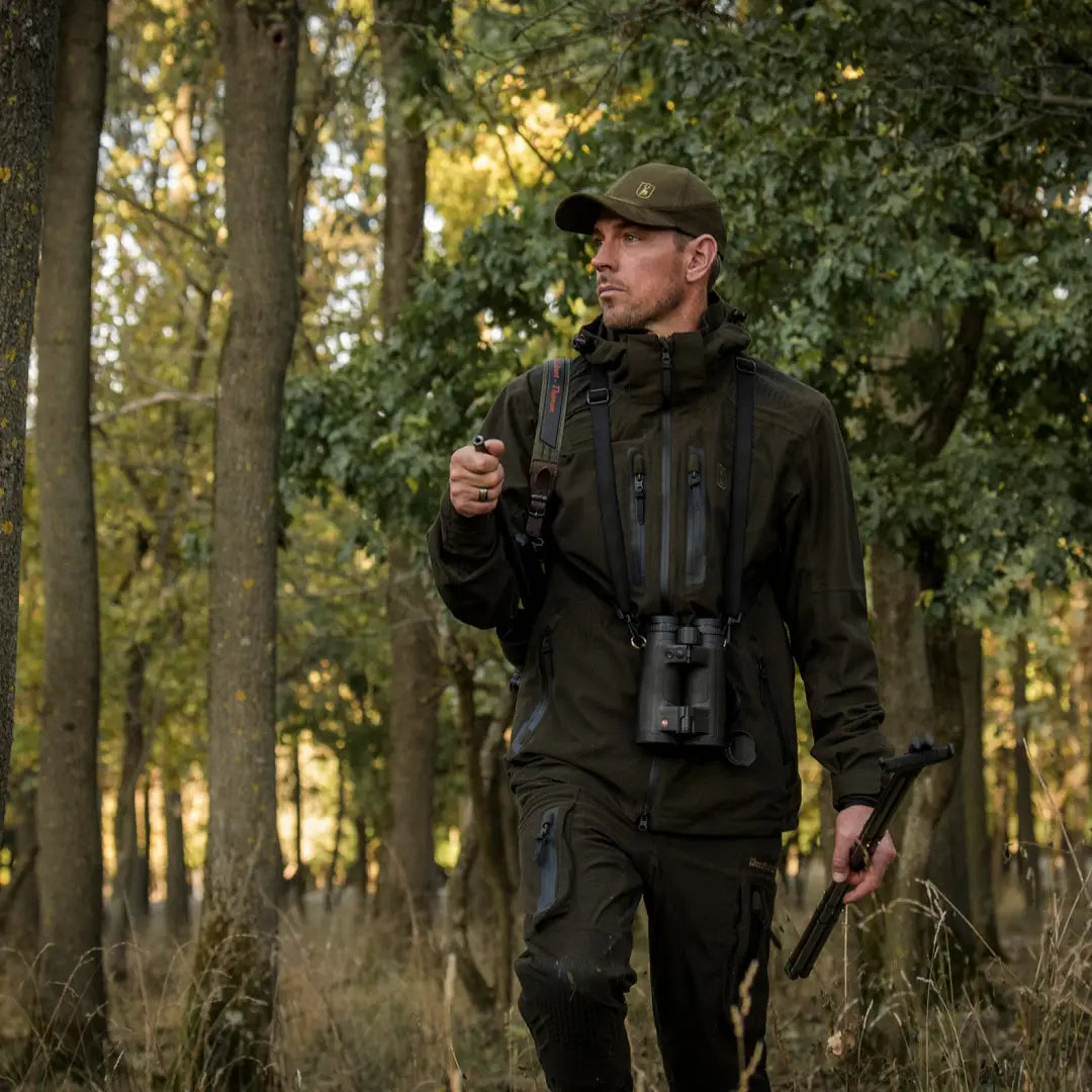 Man in forest wearing Deerhunter Game Pro Light Jacket and binoculars