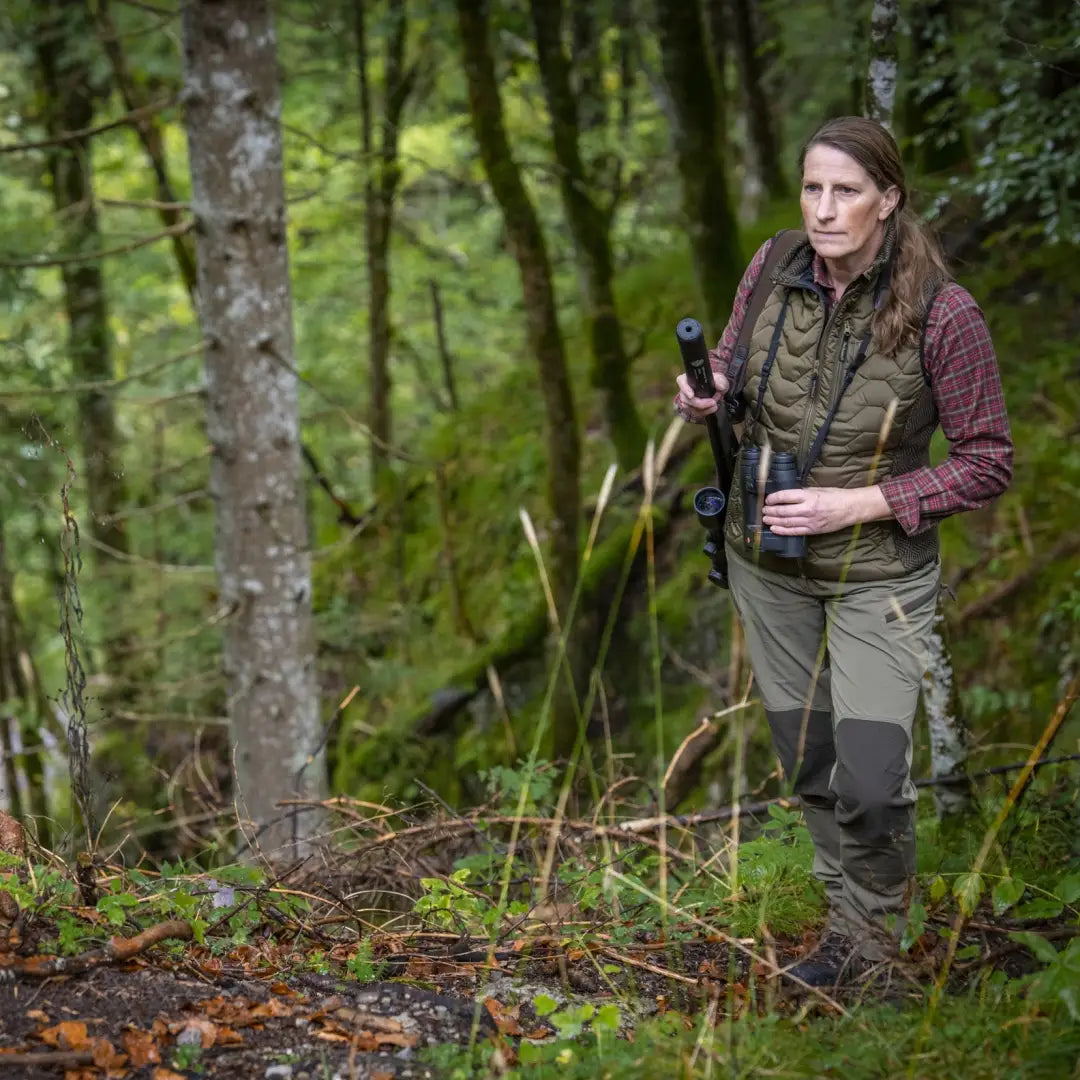 Person hiking in a forest wearing the Lady Caroline Padded Waistcoat and gear