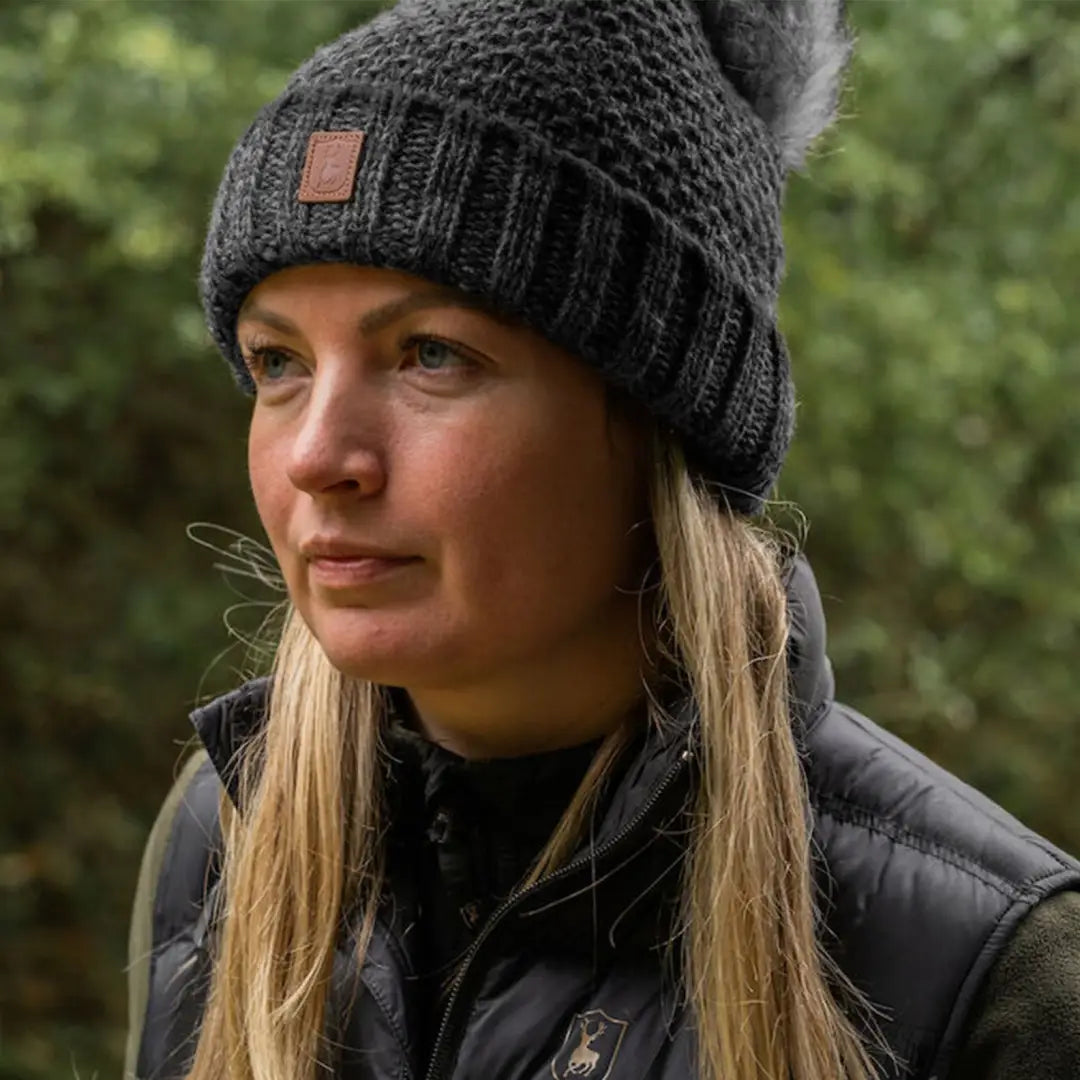 Woman in dark knit beanie and black puffer jacket braving ice-cold wind in country clothing