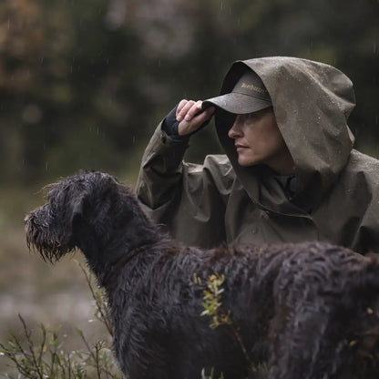 Person in Deerhunter Lady Rain Poncho with shaggy black dog outdoors