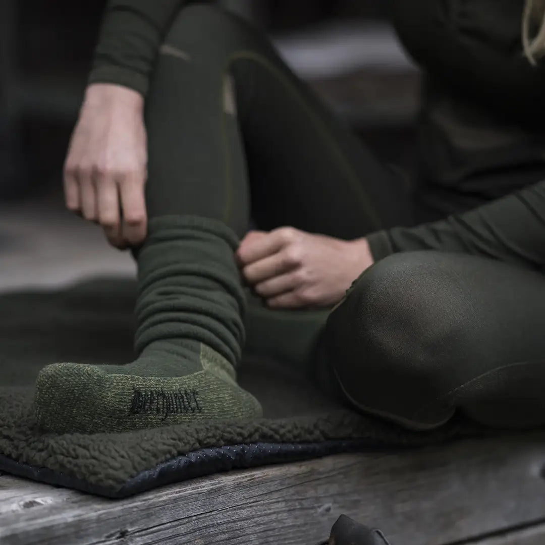 Green woolen sock on a foot, featuring Deerhunter Long Deluxe Wool design with extra soft terry