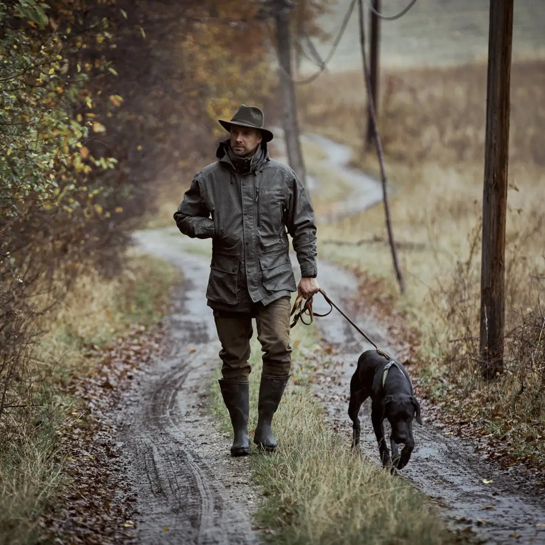 Person walking a dog on a rural path in a Deerhunter PRO Gamekeeper Hunting Jacket