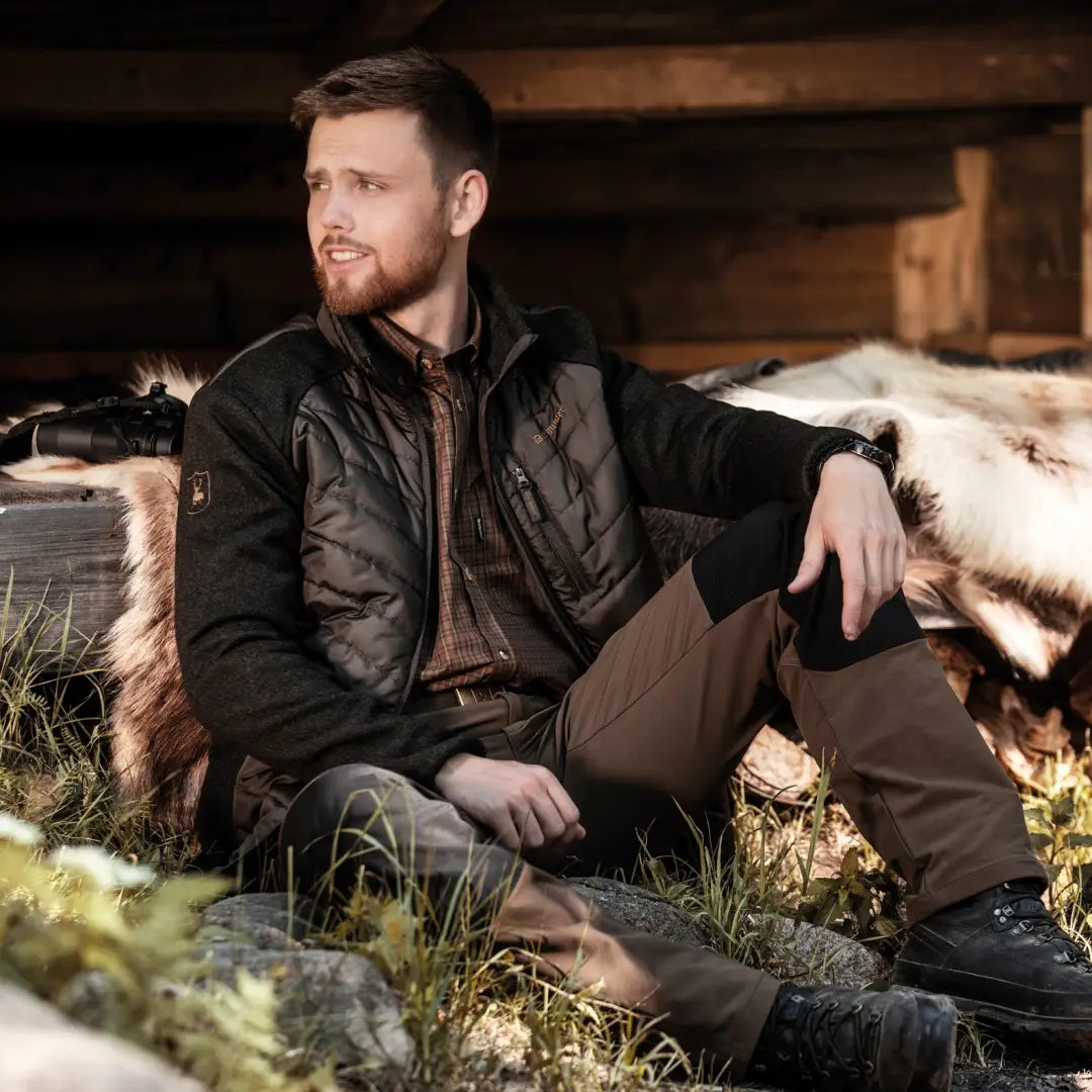 Man in a dark jacket sitting on the ground with Deerhunter Moor Padded Jacket style