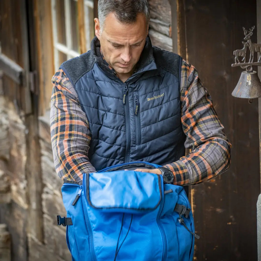 Person holding a blue waterproof duffel bag with Deerhunter Moor Padded Waistcoat