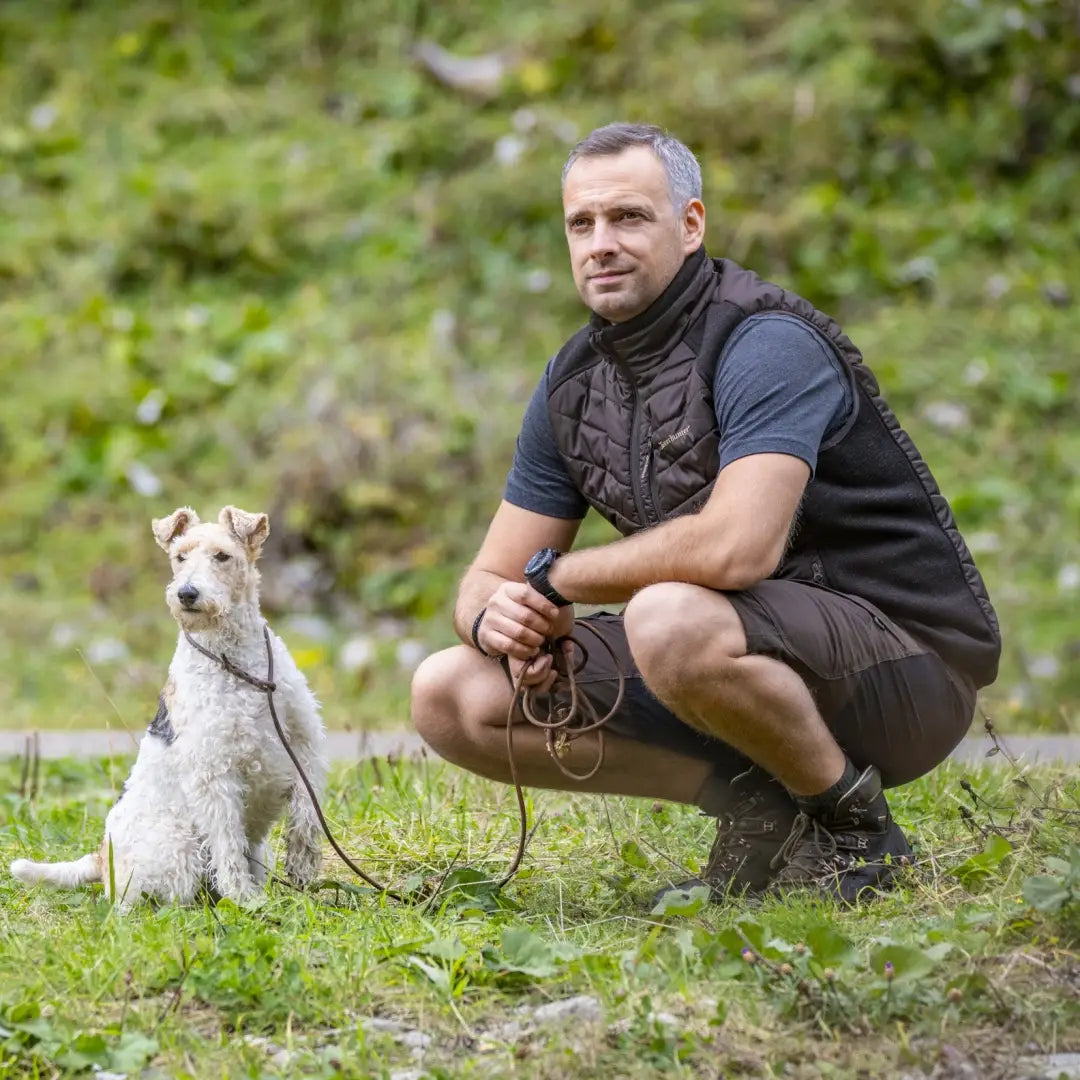 Man crouching with a small white dog in Deerhunter Moor Padded Waistcoat outdoors