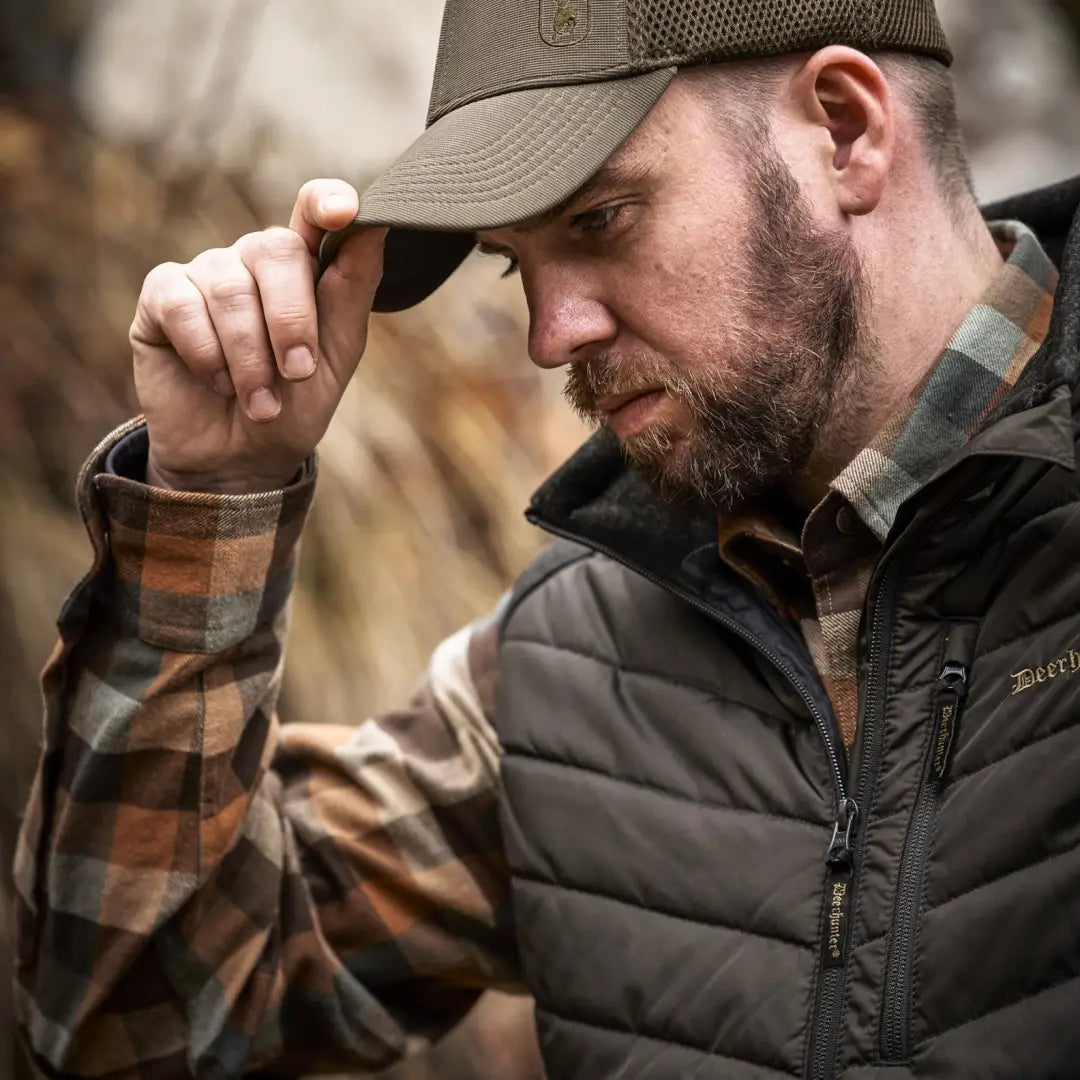 Bearded man in a cap and plaid shirt sporting a Deerhunter Moor Padded Knitted Waistcoat