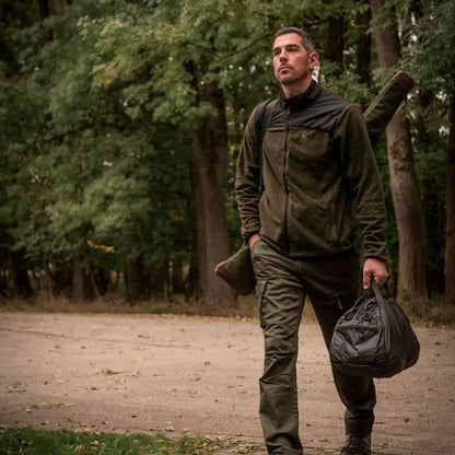 Man in outdoor gear walking a dirt path with the Northward Fleece Jacket and bag