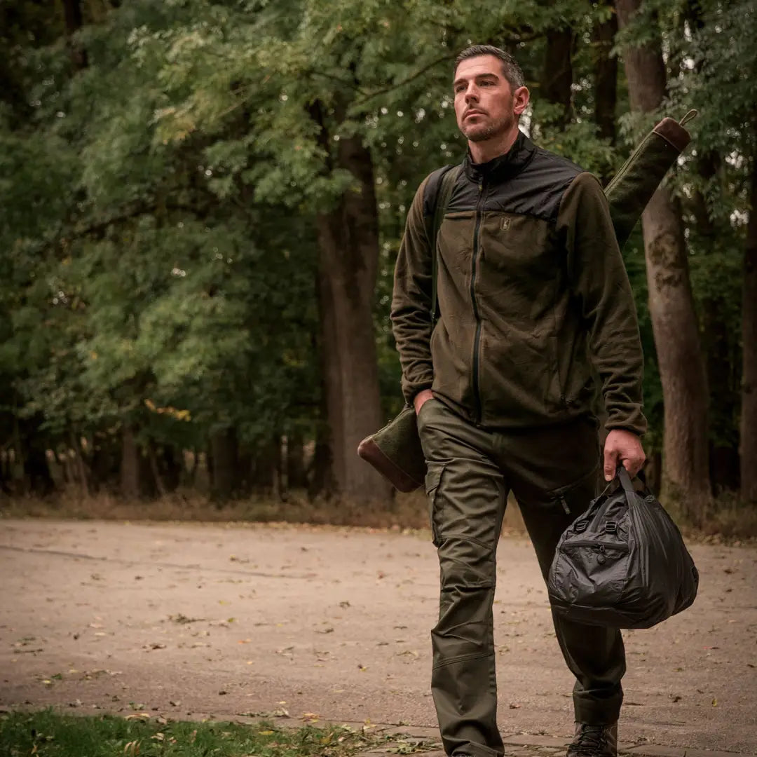 Man in Deerhunter Northward Fleece jacket hiking on a dirt path with a bag