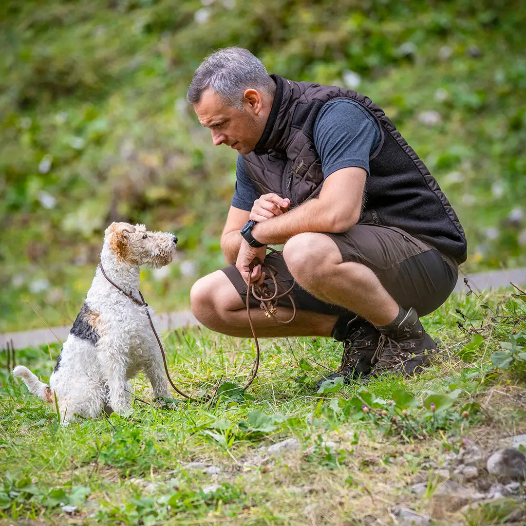 Wire Fox Terrier sits attentively by a person in Deerhunter Strike Shorts