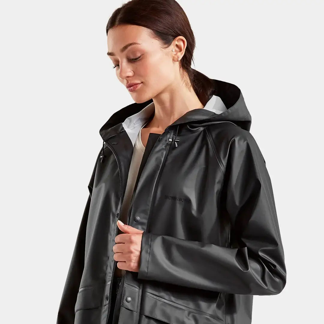 Woman in a black hooded raincoat, showcasing the Didriksons Avon Jacket 2, windproof and waterproof