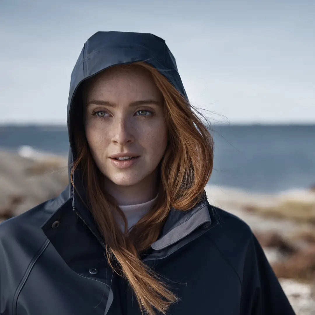 Woman with long red hair in Didriksons Elly Womens Parka against a coastal view