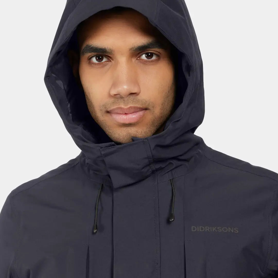 Dark hooded jacket worn by a person showcasing the Didriksons Falke Parka’s streamlined design