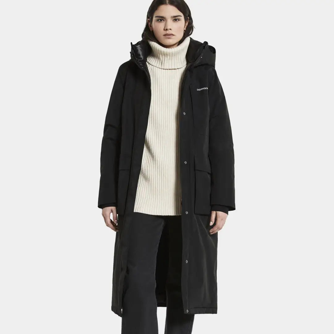 Long black winter coat with hood over cream turtleneck, Didriksons Leya Long Womens Parka