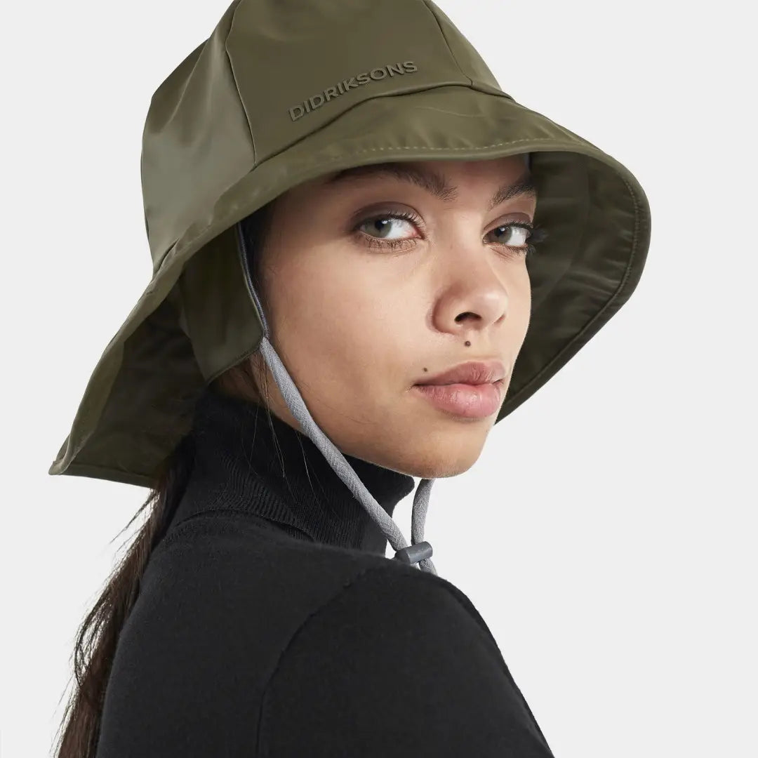 Olive green Didriksons Southwester waterproof rain hat with wide brim worn by a person