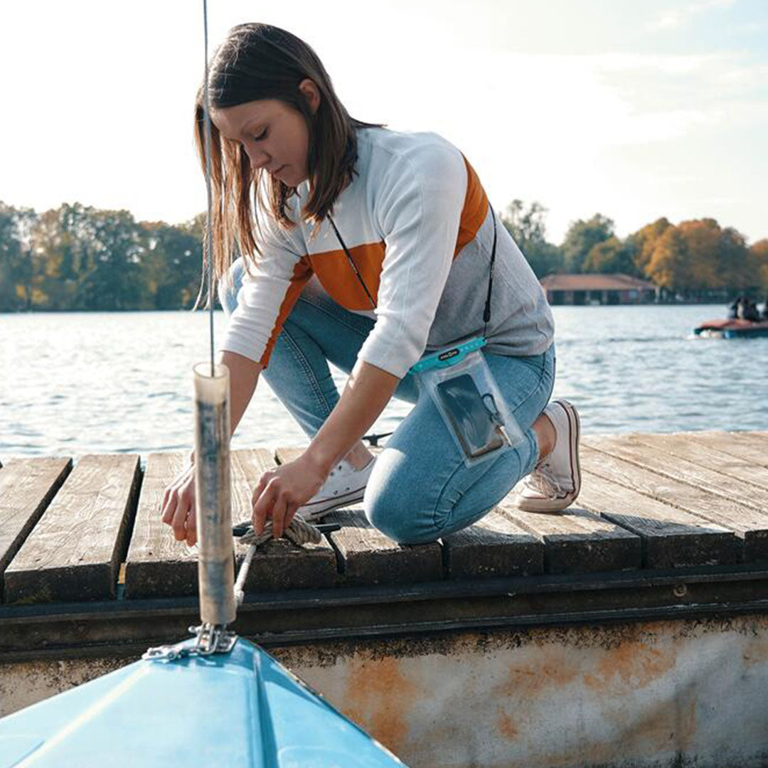 Woman kneeling on a dock, using a Fidlock dry bag for her boat repairs